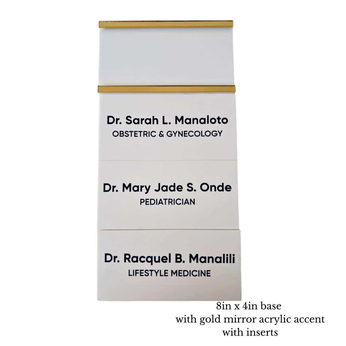 Three white personalized wall sign base and room sign inserts stacked vertically, each with a gold mirror horizontal accent bar on the top & bottom of the room sign base. The room inserts are printed with black text showing different doctor names.