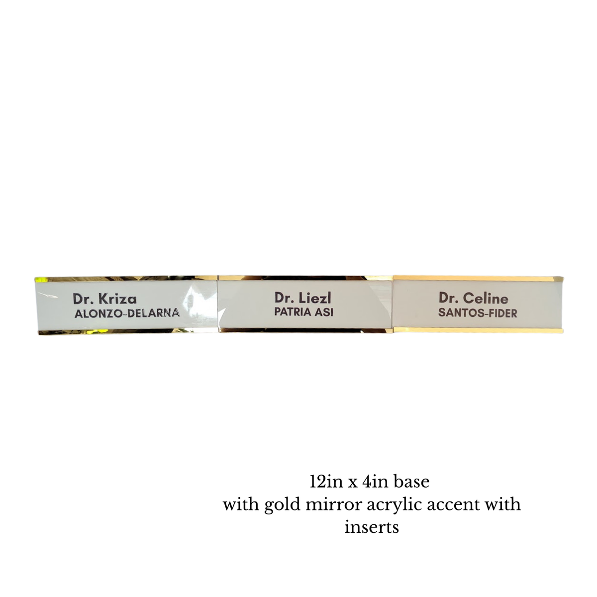 Three rectangular nameplate-style signs with gold mirror acrylic accents and printed names, shown on a white background with text below reading '12in x 4in base with gold mirror acrylic accent with inserts'.